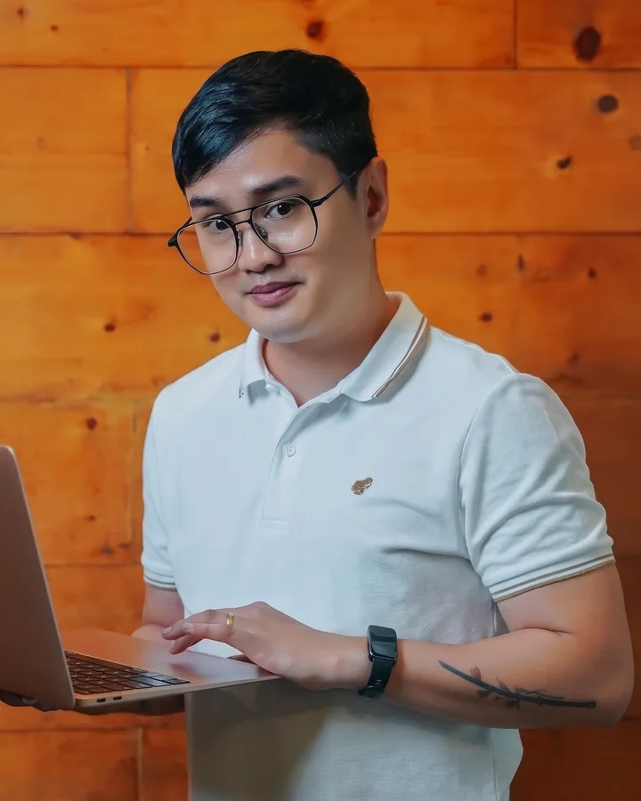 Jay Say holding a laptop and smiling at the camera